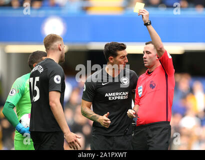 Arbitro Andre Marriner (destra) assegna un cartellino giallo a Brighton e Hove Albion è Adam Webster (sinistra) su un fallo su del Chelsea montaggio Mason durante il match di Premier League a Stamford Bridge, Londra. Foto Stock