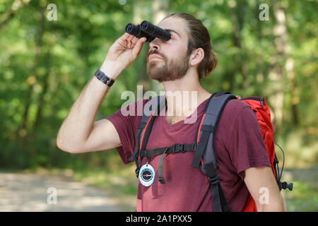 Uomo con guardando attraverso il binocolo in legno Foto Stock