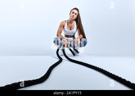 Il sudore stanco ragazza guardando la telecamera, seduto al centro sportivo, cordini. a piena lunghezza foto. Tempo libero, tempo di ricambio Foto Stock