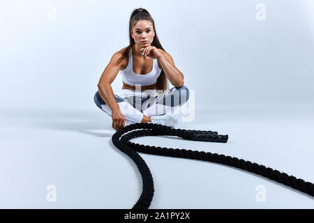 Buona ricerca piacevole donna seduta con le gambe incrociate a palestra. a piena lunghezza foto. Foto Stock
