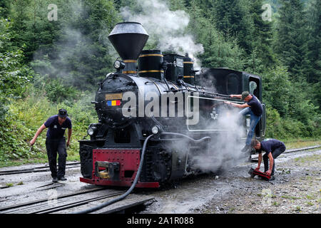 Tre uomini al lavoro sulla locomotiva del vecchio romanian motore a vapore in treno da Resita corporation nella valle di Viseu, Romania Foto Stock