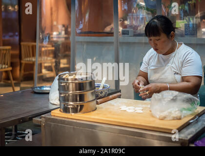 Xian, Cina - Agosto 2019 : Donna porzionamento impasto di farina per la preparazione delle famose ciambelle baozi in una piccola panetteria locale sulla strada a musulmano Foto Stock