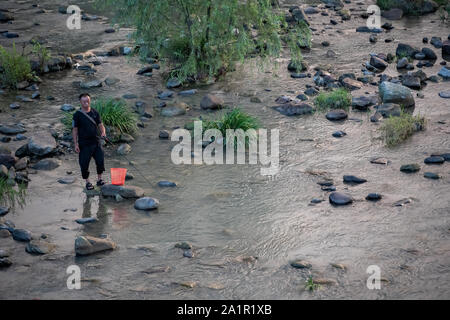 Wulingyuan, Cina - Agosto 2019 : pescatore cinese in piedi in un fiume poco profondo Foto Stock