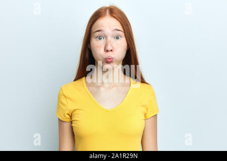 Grave crazy funny donna brucia le guance, sleepy espressione, stufi di routine mattutina, vuole vacanze, vestito in Giallo casual T-shirt , isolato o Foto Stock