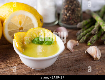 Aglio e salsa di limone per pasta, pesce o pollo, servito con asparagi su tavola in legno rustico Foto Stock