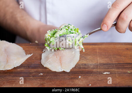 Preparazione del pesce bianco involtini di tilapia farcite con un trito di broccoli e asparagi Foto Stock