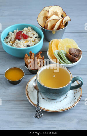 Colazione: fiocchi d'avena con pezzi di frutta e confettura di fragole, pezzi di canditi di ananas, kiwi e mango, fichi secchi, mela e pera chips, miele in Foto Stock