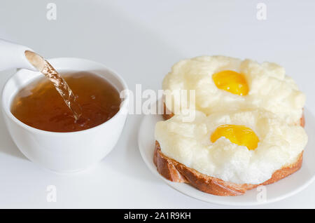 Caldo, uova sandwich per colazione. Versare il tè in una tazza. Messa a fuoco selettiva Foto Stock