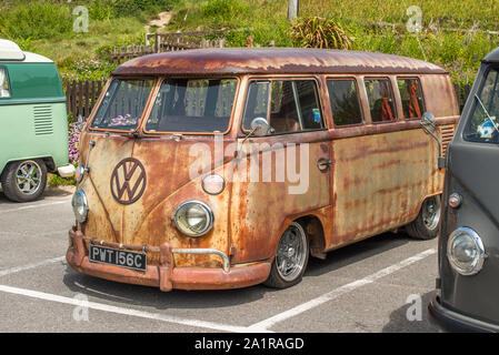 Righe del Classico Volkswagen camper parcheggiato a Porthtowan spiaggia parcheggio sul West Cornwall coast, Inghilterra, Regno Unito. Foto Stock