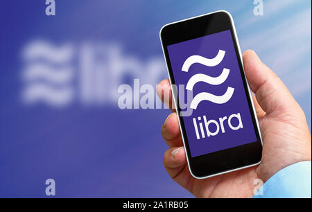 Benon, Francia - 28 settembre 2019:Man tenendo un smartphone nella sua mano con il logo di libra, la nuova moneta crypto creato da facebook Società. Le sfocature Foto Stock