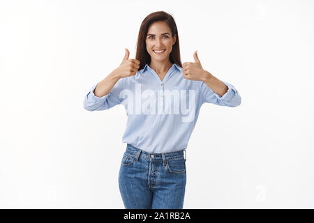 Animati belli assertivo unione brunette donna, mostra Thumbs up risposta positiva, come scelta eccellente, approvare idea, sorridente largamente, supporto Foto Stock