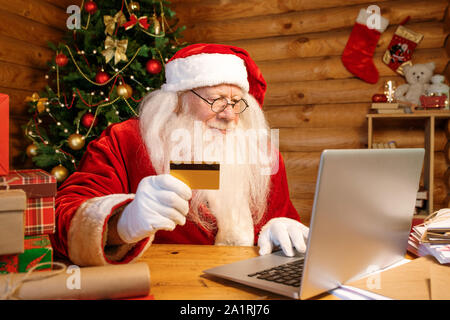 Coperta da un guanto Santa in costume tenendo la scheda di plastica facendo ordine in internet prima di Natale Foto Stock