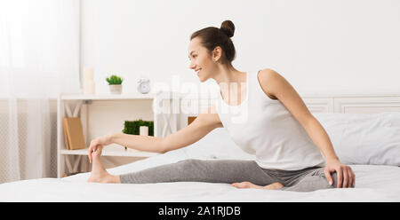 Montare donna gambe di stiramento nel suo letto la mattina presto Foto Stock