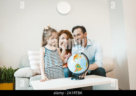 Andando su avventura, mamma, papà e figlia studia globo. Foto Stock