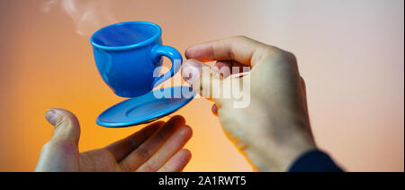 Blu flottante tazzina di caffè espresso con le mani. Visuale in prima persona. Mock up di volare in aria tazza di caffè caldo. Levitare concept Foto Stock