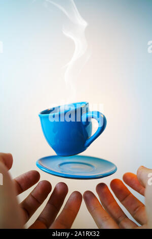 Blu flottante tazzina di caffè espresso con le mani. Visuale in prima persona. Mock up di volare in aria tazza di caffè caldo. Levitare concept Foto Stock