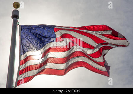 Sole splende attraverso un fllag DEGLI STATI UNITI sulla base del Monumento di Washington a Washington, DC. Foto Stock