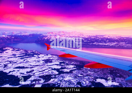 Una vista straordinaria dalla finestra del velivolo durante il tramonto su montagne in Svizzera Foto Stock