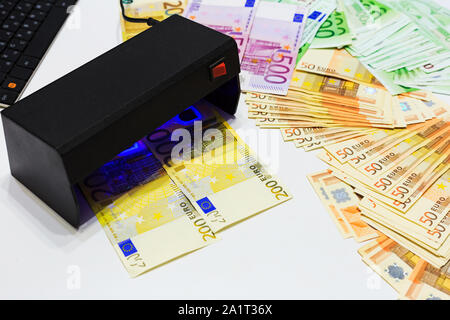 Soldi finti test - banconote in euro controllo di autenticazione in UV valuta le luci del rivelatore. La contraffazione di banconote, controllo presso la banca dal cassiere, ba Foto Stock
