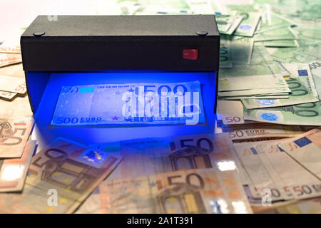 Soldi finti test - banconote in euro controllo di autenticazione in UV valuta le luci del rivelatore. La contraffazione di banconote, controllo presso la banca dal cassiere, ba Foto Stock