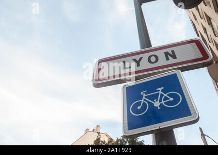 Lione, Francia - Luglio 17, 2019: cartello stradale che indica l'entrata a Lione con un segno di biciclette. Questo segno è un Francese standard targhetta visibile in ogni entr Foto Stock