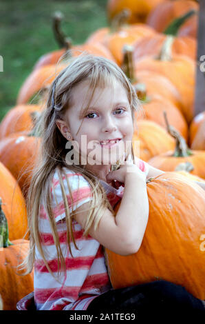 Un adorabile bimba bionda sceglie la sua preferita la zucca da una trafficata Michigan STATI UNITI fattoria di zucca Foto Stock