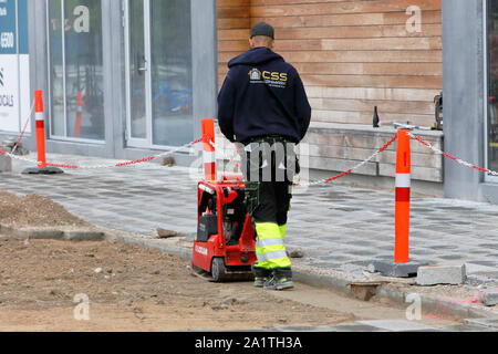 Copenhagen, Danimarca - 4 settembre, 2019.: vista posteriore di un lavoratore di sesso maschile con un rosso vibrante compattatore piastra di compattazione di ghiaia alla costruzione di strade si Foto Stock