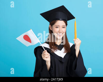 Felice femmina asiatica studente laureato che mostra la bandiera del Giappone Foto Stock