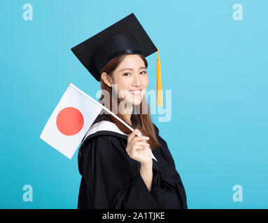 Felice femmina asiatica studente laureato che mostra la bandiera del Giappone Foto Stock