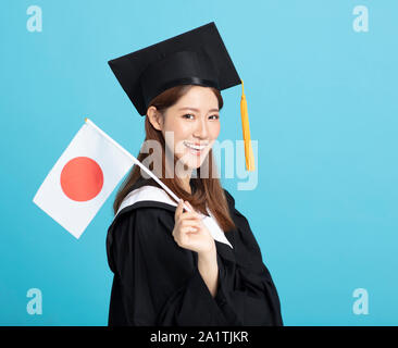 Felice femmina asiatica studente laureato che mostra la bandiera del Giappone Foto Stock