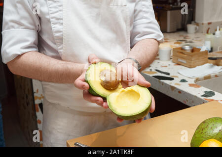 Lo chef è che mostra un avocado tagliato in due pezzi, all'interno della pietra Foto Stock