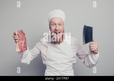 Ritratto di lui crazy attraente bello allegro allegro macellaio positivo guy holding carni fresche e coltello in mano armi aperto bocca isolate su Foto Stock