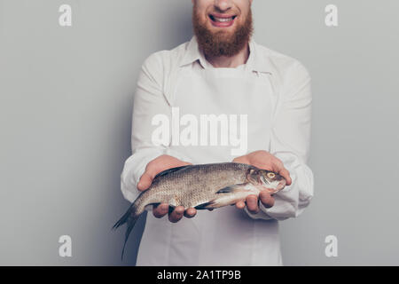 Ritratto di lui bella attraente bello allegro ottimista positiva macellaio esperto guy holding dando mostra il pesce in armi mani ricetta a base di pesce Foto Stock