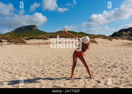 La donna nel cappello e occhiali da sole sulla spiaggia di Cala Mesquida Mallorca Spagna, rende il gesto dab Foto Stock
