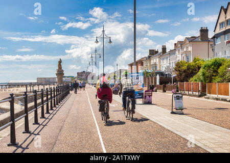 15 Giugno 2019: Lowestoft, Suffolk, Regno Unito - i ciclisti sul lungomare su una luminosa giornata estiva, persone che passeggiano e il molo di distanza. Foto Stock