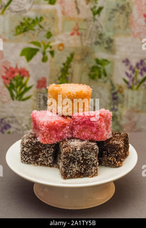 Colorato dessert Australiano con torta Lamingtons impilati e servita su una torta di stand Foto Stock