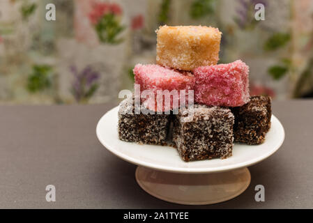 Colorato dessert Australiano con torta Lamingtons impilati e servita su una torta di stand Foto Stock