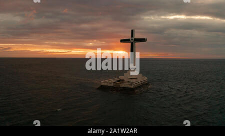 Croce cattolica nel cimitero affondata nel mare al tramonto, antenna fuco. colorato cielo durante il tramonto. Grandi crucafix segnando il sottomarino sunken cimitero, CAMIGUIN ISLAND Filippine. Foto Stock