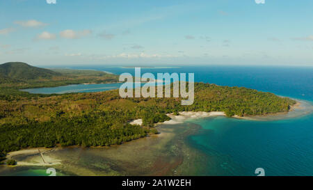 Isola tropicale Balabac ricoperta di verde foresta di pioggia contro il cielo blu con nuvole e mare blu dal di sopra. Seascape: oceano e cielo. Palawan, Filippine Foto Stock