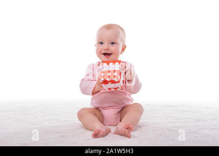 Bambina piccola e una scatola con un regalo su un bianco. Foto Stock