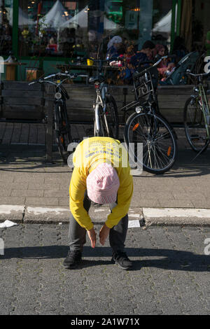 Sint Niklaas, Belgio, 8 settembre 2019, Orientale donna con cappello praticato Falun Dafa, si piega e consente a entrambi i bracci appendere Foto Stock