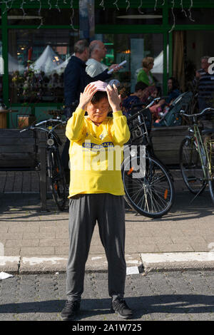 Sint Niklaas, Belgio, 8 settembre 2019, Orientale donna con cappello praticato Falun Dafa, respira potente e abbassare i bracci verso il basso Foto Stock