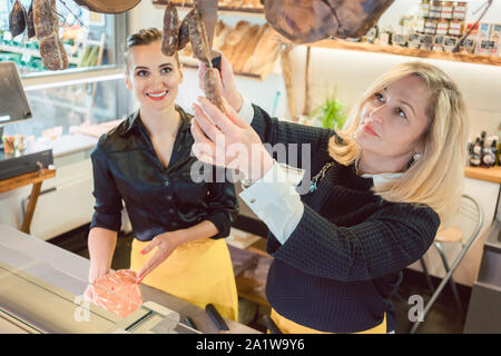 Shop assistant donne la vendita di formaggio e salumi in deli Foto Stock