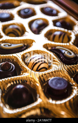 Cioccolatini di forme diverse in una scatola dorata, una vista in prospettiva e la sfocatura Foto Stock