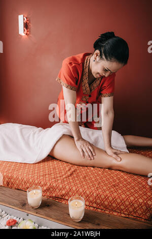 Massaggiatore asiatico facendo massaggio ai piedi per donna in spa salone Foto Stock