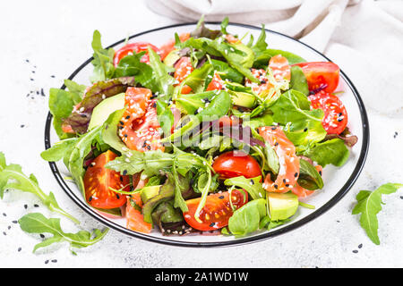 Insalata di salmone con foglie di colore verde su bianco. Foto Stock