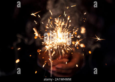 Sparkler sfondo per il compleanno, festa, anno nuovo, Diwali, vacanze di Natale. Ragazza con scintillante sparkler isolato in sfondo nero. Foto Stock