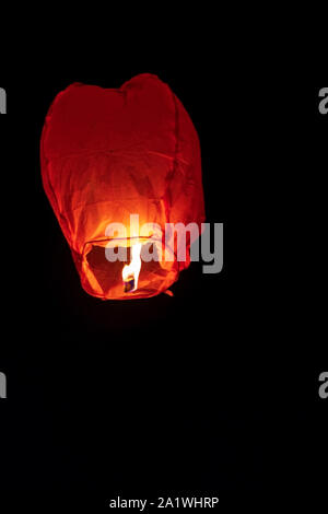 Red Sky lantern vola in alto altamente nel cielo di notte durante il Diwali, nuovo anno celebrazione con copia spazio. Unica lanterna oscillante durante fuochi d' artificio festi Foto Stock