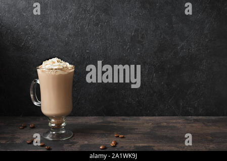 Irish Coffee con panna montata e chicchi di caffè nero su sfondo di legno, copia dello spazio. Foto Stock
