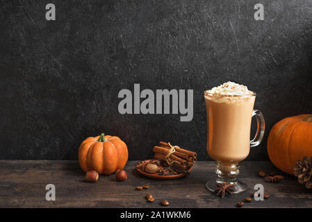 Pumpkin Spice Latte nero su sfondo di legno, copia dello spazio. Stagionale autunnale di bere caffè con spezie e zucche di organico. Foto Stock